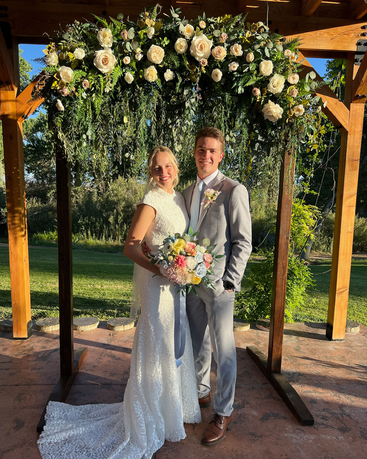 Reception featuring Cascading Vines Tan Ivory Floral Wedding Arch in backyard in Fallon, Nevada.